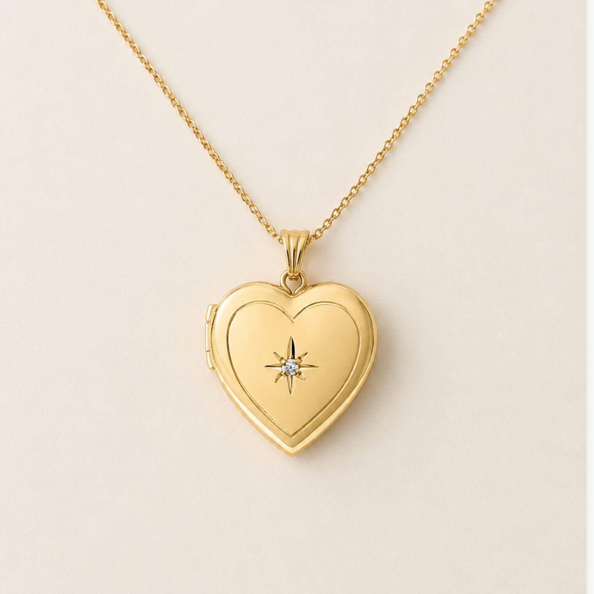 A 14k gold filled heart-shaped locket pet memorial necklace with a small starburst and diamond in the center, shown on a delicate gold chain against a light beige background.