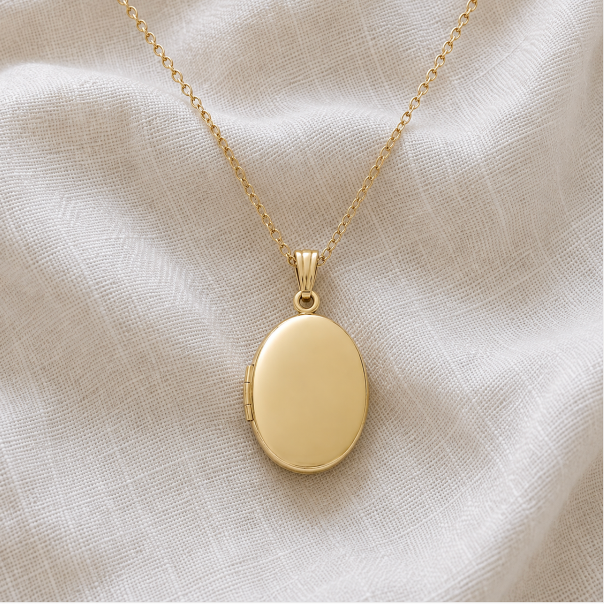 A 14K gold filled gold oval locket pet memorial necklace with a matching chain, displayed on a textured off-white fabric background.