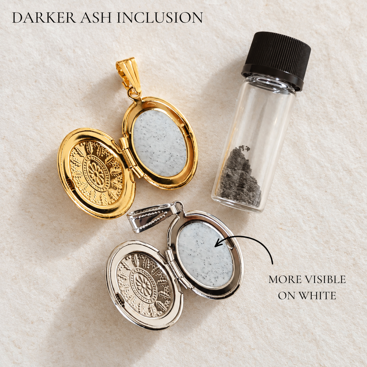 Two oval locket-style jewelry pieces with open gold and silver halves are shown on a light textured background, alongside a small clear vial containing dark gray ash. Text reads 'DARKER ASH INCLUSION' and 'MORE VISIBLE ON WHITE' to explain the visible inclusions.