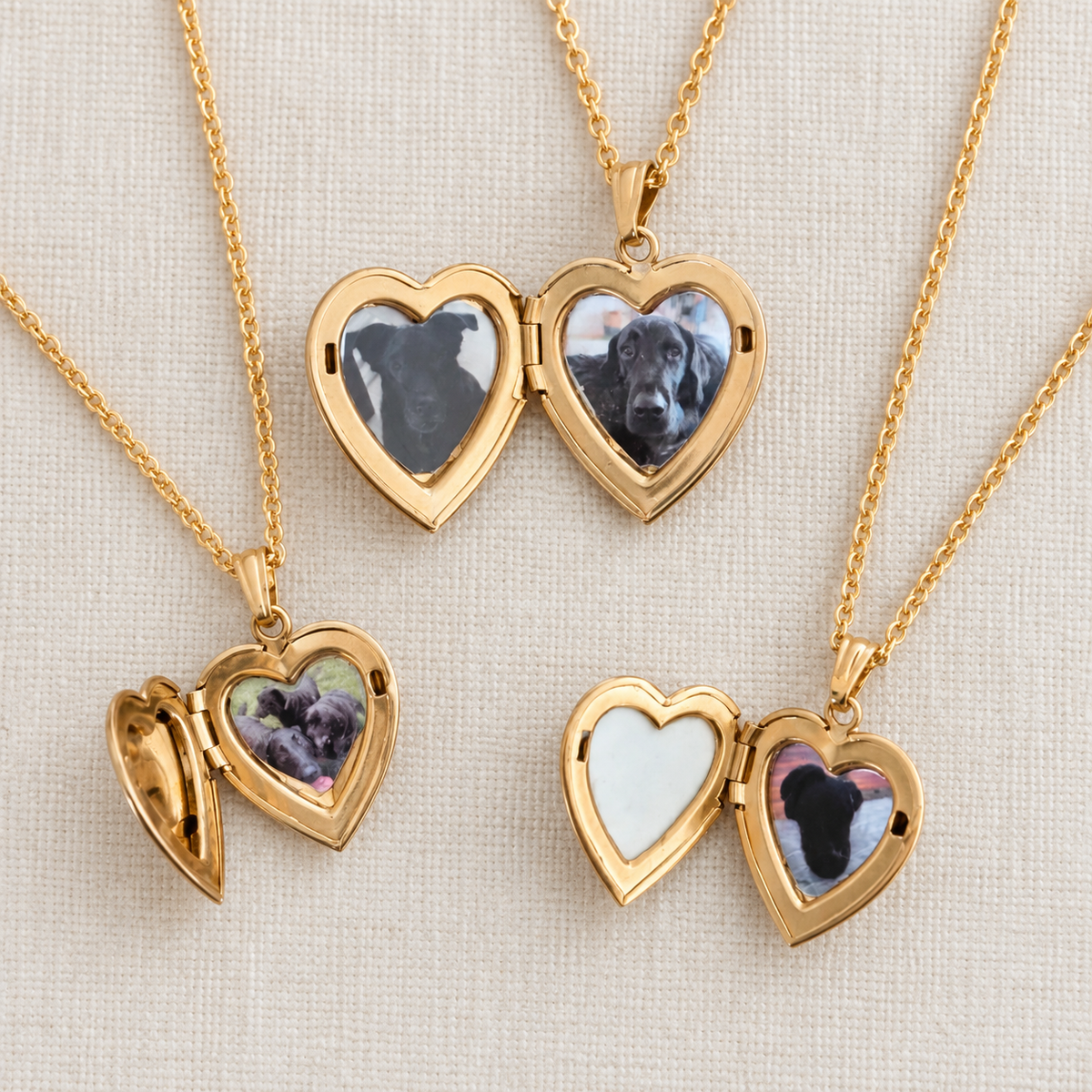 Four gold heart-shaped locket necklaces on a textured beige fabric background. Three are open to show custom pet photos inside, and one is closed showing a white inlay.